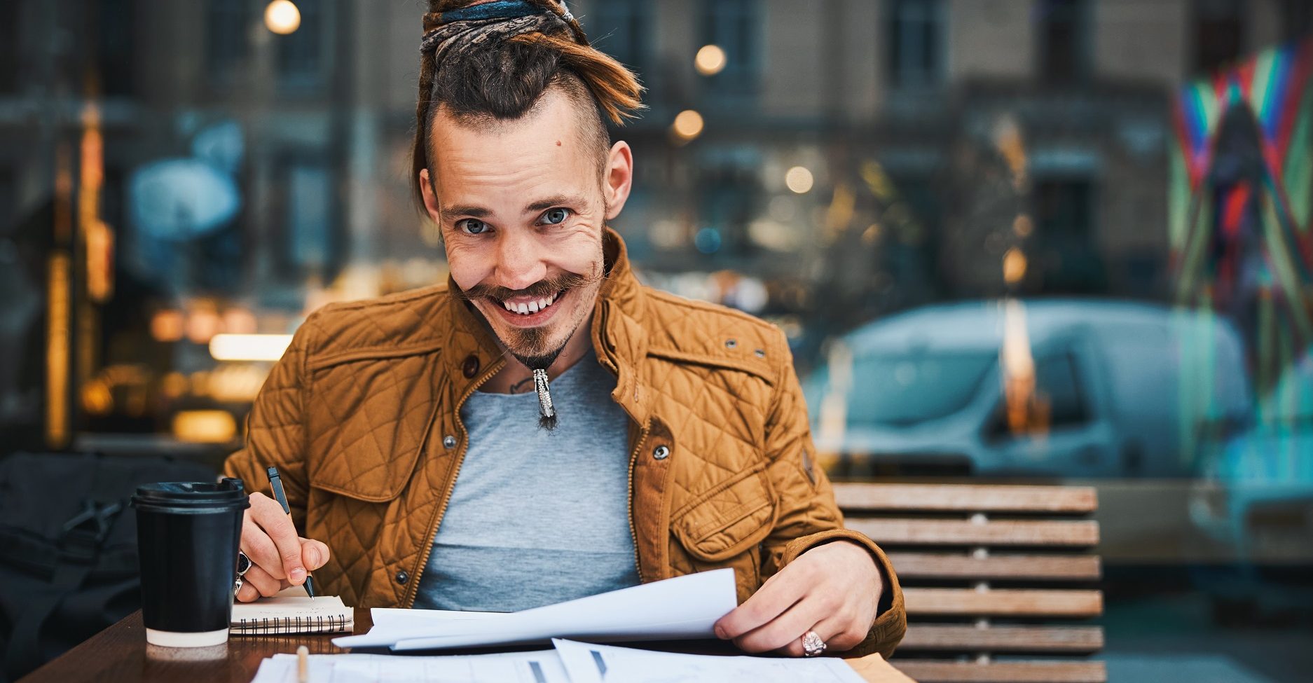 cheerful hipster with sketchbook in urban cafe